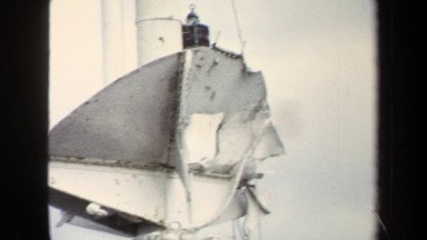 1970: tall white pole with waving red flag and ropes has bent metal plate