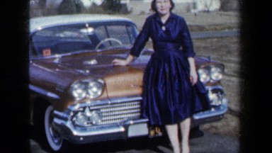 1959: A Woman in a Dress Beside a Classic Car in New York