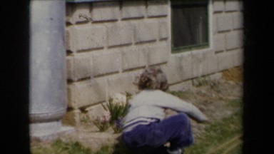 1959: A Blond Child Sits on a Patio Next to Two Large Metal Jars New York