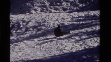 1981: person sliding short way down slope on small disc and then slowly falling