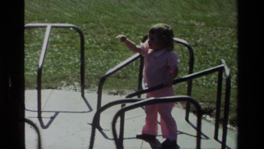 1979: a little brunette girl is being spun around slowly on a merry go round by