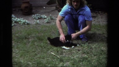 1979: A Woman Outside Playing and Scratching a Cute Black and White Kitten