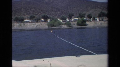 1977: a person water skiing behind a boat on a beautiful lake