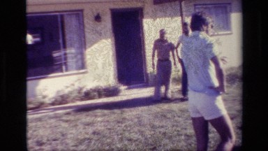 1977: A Group of People Walks and Photographs in the Front Yard of a House Lake
