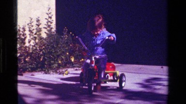 1979: A Small Child Rides Her Tricycle in a Driveway on a Cool Day California