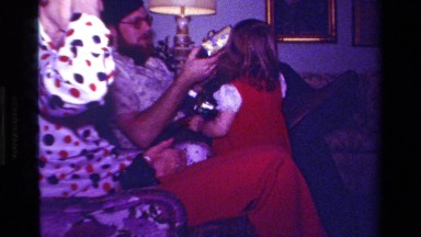 1979: girl helping adult open present, puts bow on her head CALIFORNIA
