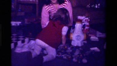 1979: Child Opening Christmas Present with Toys in Background California