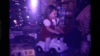 1979: Woman Watching Little Girl Play with Toy Around Christmas Tree
