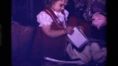 1979: child opening christmas present with other toys and christmas tree