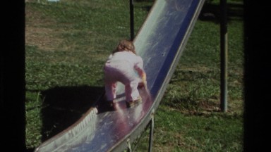 1979: baby climbing on a slide at a park feeling funny. CALIFORNIA