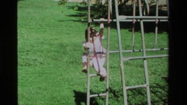 1979: woman helps young girl who loses footing while climbing on a playground