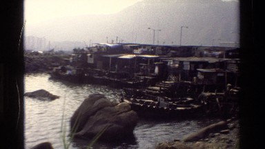 1984: A Series of Houseboats Sit Docked Near a Large City in Hong Kong