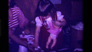 1979: little girl in red playing with a make believe baby with the help