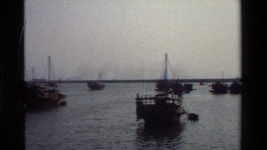 1984: Boats Sit Idle in a Coastal Area with a Stone Structure and Mountains