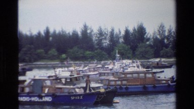 1984: boats of various side floating gently down a calm river SINGAPORE
