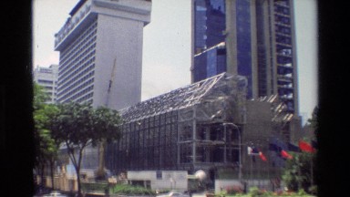1984: View of a Construction Site in a Scenic, Populated Urban Area Near Flags