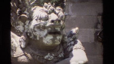 1984: statue with bulging eyes and ornate costume stands by wall