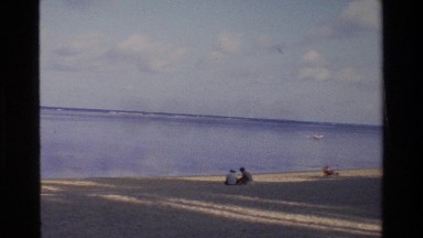 1984: People in the Distance Sitting on a Beach in Front of a Placid Ocean