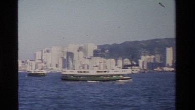 1984: A Large Battleship and Smaller Ships Float Near Hong Kong's City