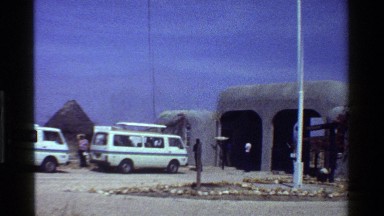1983: a group of white vans parked along a community of huts KENYA