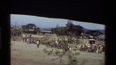 1983: a crowd of people mill about in a field of dry grass KENYA