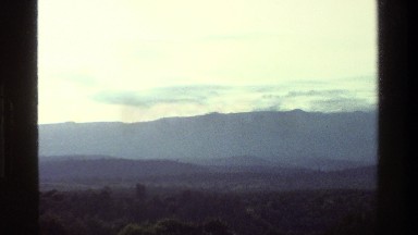 1983: Forested Hills Stretch Out From the Base of a Mountain Range