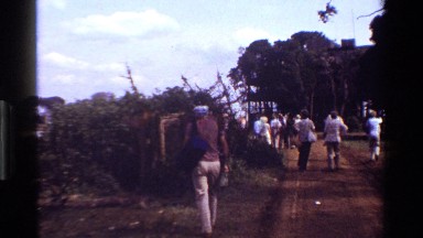 1983: people walking about as an older man heads towards a small wooden