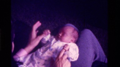 1975: a person sits playing with a small baby laying in it's lap CALIFORNIA