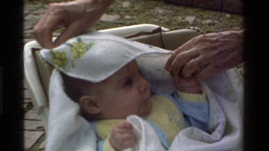 1975: a lady putting a blanket on her baby's head CALIFORNIA