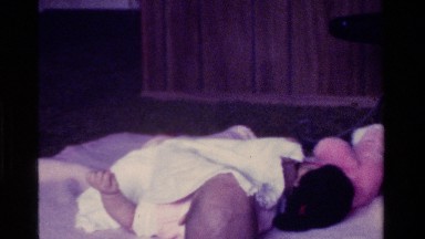 1975: baby plays with blanket and mouse plush while lying on back CALIFORNIA