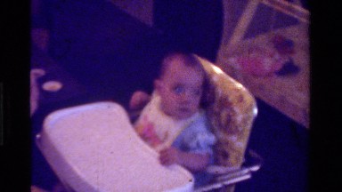 1975: infant in high chair being fed CALIFORNIA