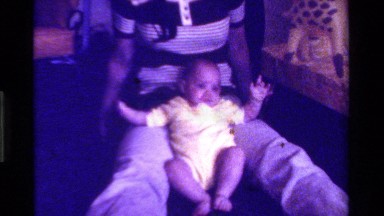 1975: infant sitting on floor propped up by an adult CALIFORNIA