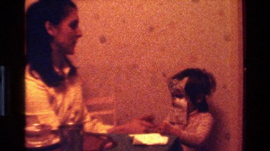 1977: a mother playing with her child by having the mask in home CALIFORNIA