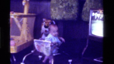1975: Baby Scoots Across Floor in Old Walker While Golf Game Plays on TV
