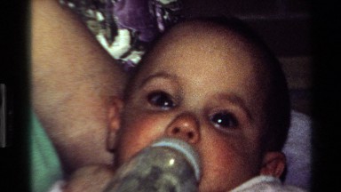 1977: a mother feeding her small baby with fluids from a feeding bottle