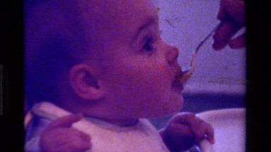 1975: an adult feed a baby food from a spoon in a high chair CALIFORNIA