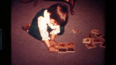 1977: a happy little girl puts together a child's puzzle with an adult