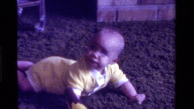 1975: a baby trying to crawl across shag carpet while it watches something