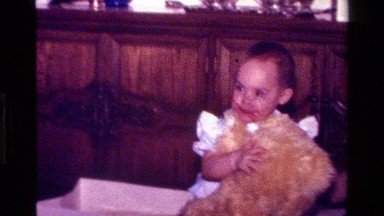 1977: a baby grabs a teddy bear and puts it in a chair CALIFORNIA