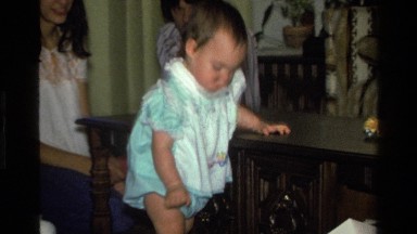 1977: child playing with stuffed bear while parents are watching