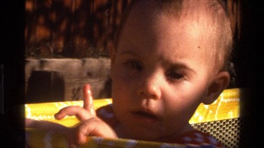 1977: a baby with sin in her face in her playpen CALIFORNIA