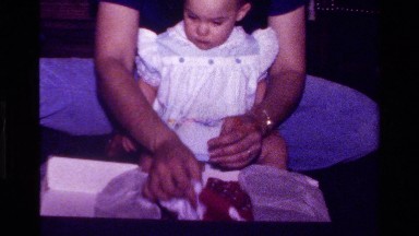 1977: adult helps toddler open and model new dress CALIFORNIA