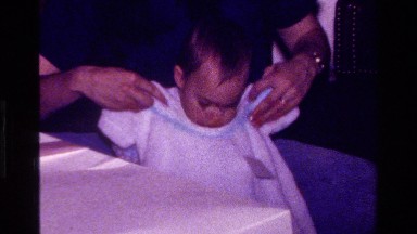 1977: Holding a Knitted Dress Up to a Baby in California