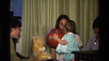 1977: toddler plays with ball in home with surrounding adults CALIFORNIA