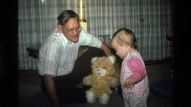 1977: A Mature Man Holding a Teddy Bear Plays with a Female Toddler CALIFORNIA
