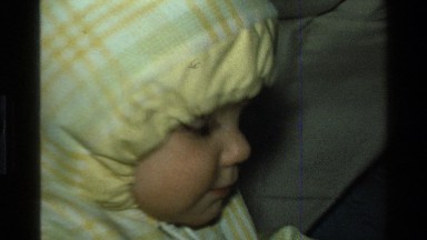 1977: a baby in a jacket holding a newspaper CALIFORNIA