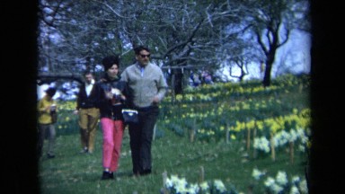 1969: a man and a women are walking in a garden as others move around CALIFORNIA