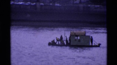 1969: A Shallow Boat and Ship Float on a River in London on an Overcast Day