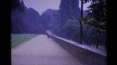 1969: People Stand Along a Long Path Next to Grass and Trees London England