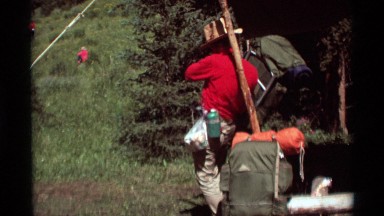 1975: a man adjusting his backpack on a hiking and camping trip. AGATE SPRINGS
